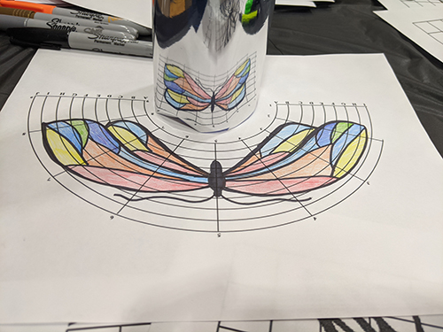 Like the reverse of a fun-house mirror, at the Anamorphic Art Station, participants would transform a picture on a grid to a warped grid and then watch as the picture became un-warped with a mirror. (Image courtesy of Marley Dewey.)